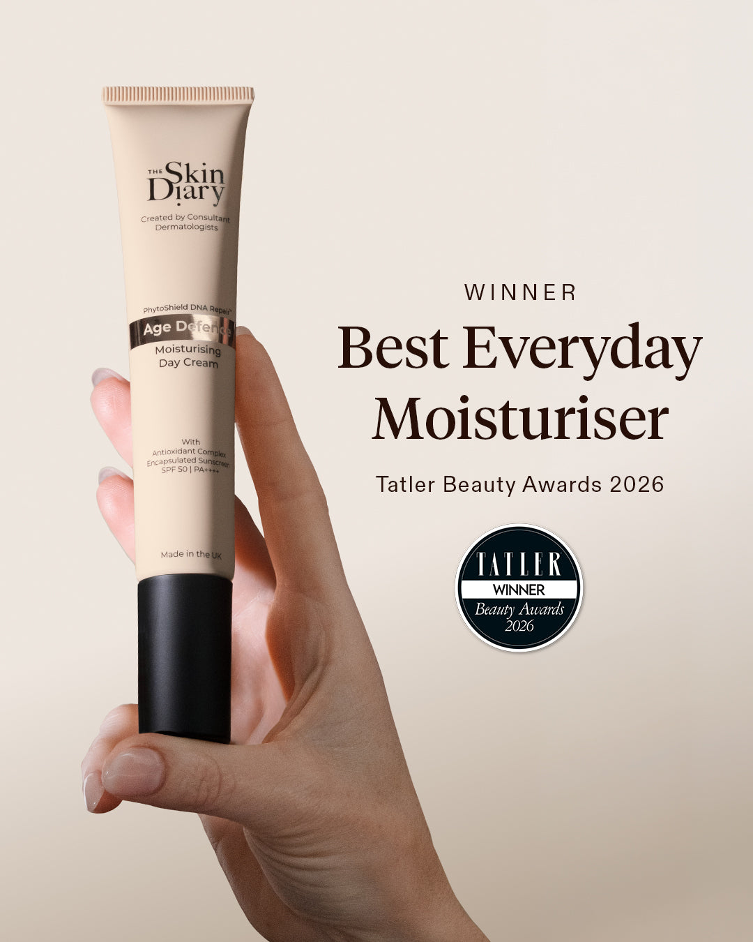 A hand holds a tube of Skin Diary Age Defining Moisturising Day Cream against a warm beige background, with award text reading 'Winner Best Everyday Moisturiser Tatler Beauty Awards 2026' and a Tatler badge.