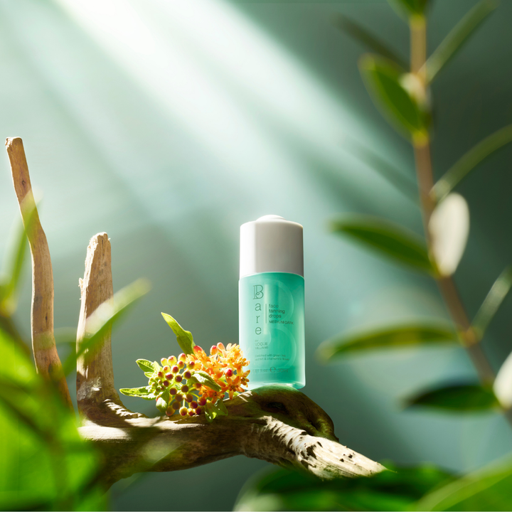 Green skincare bottle on a branch with leaves and flowers in the background