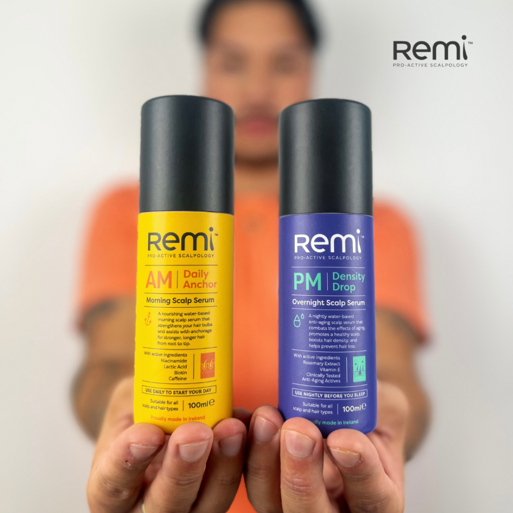Two Remi scalp serum bottles, one yellow and one blue, held by a person with a blurred background.
