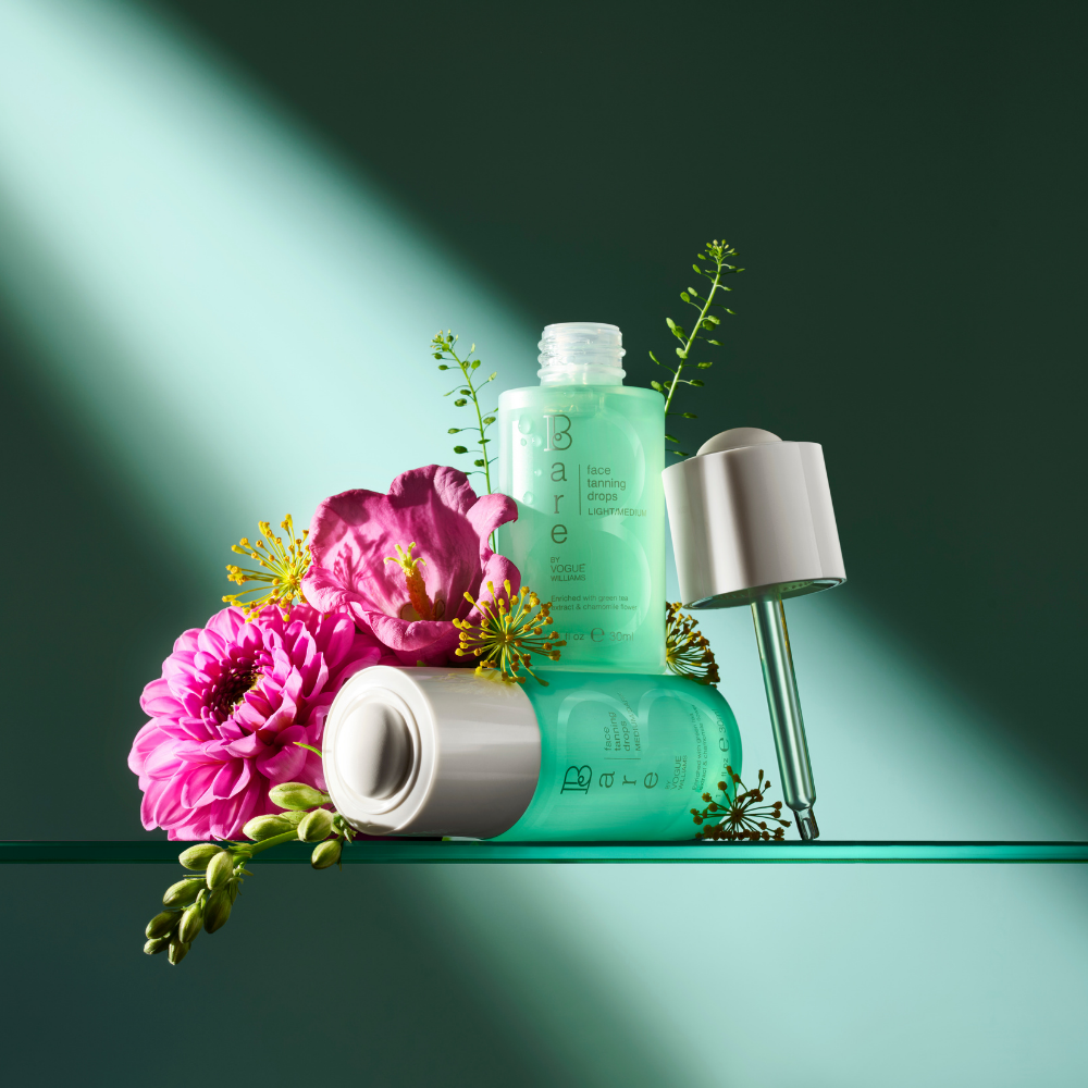 Bare by Vogue face tanning drops in translucent aqua bottles with silver caps and floral accents