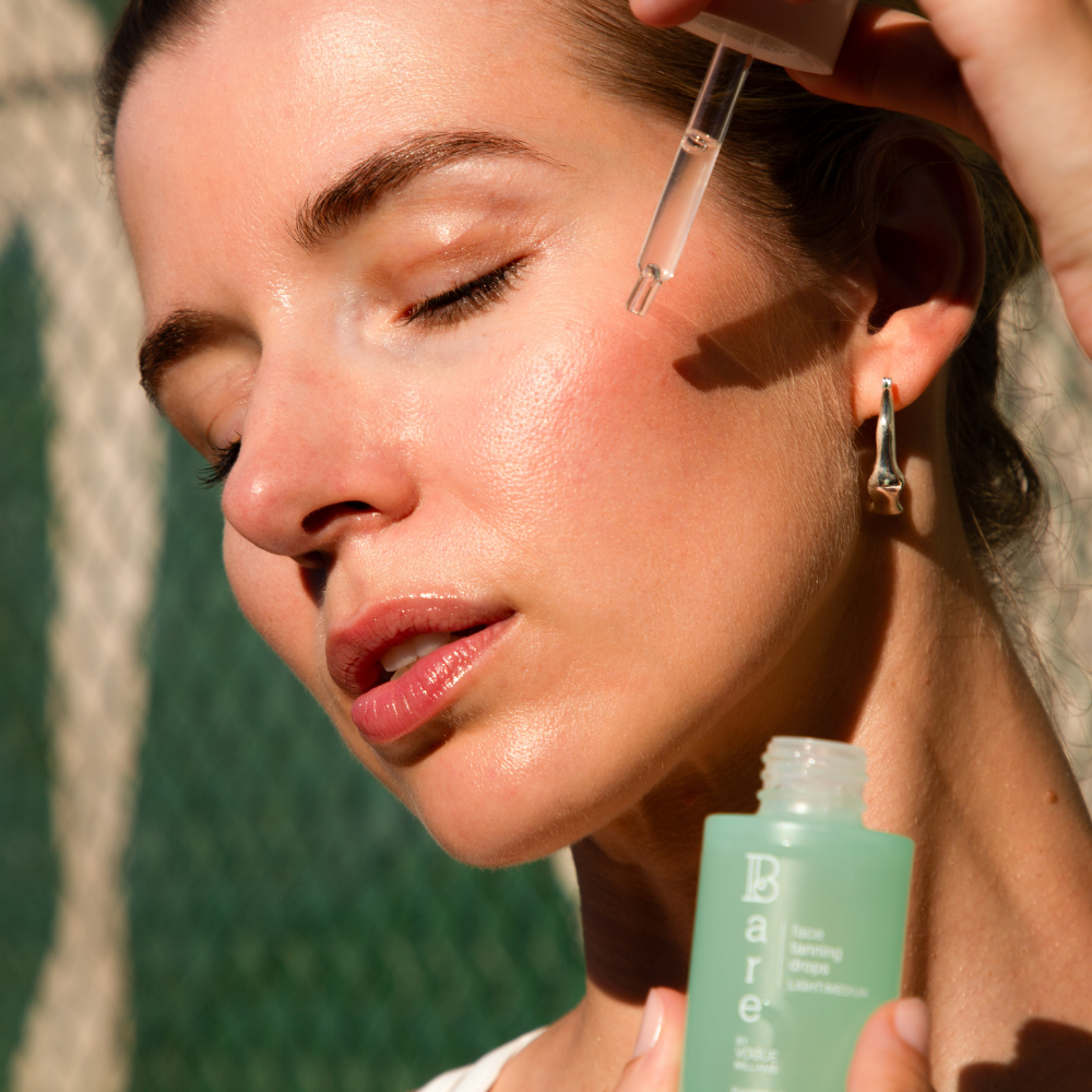 Bare by Vogue face tanning drops in a mint green bottle with pipette applicator beside a woman's glowing face