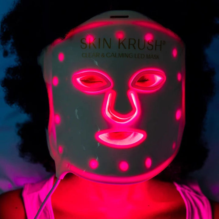 Clear and Calming LED Mask in dark flexible material glowing with bright pink-red LED facial features