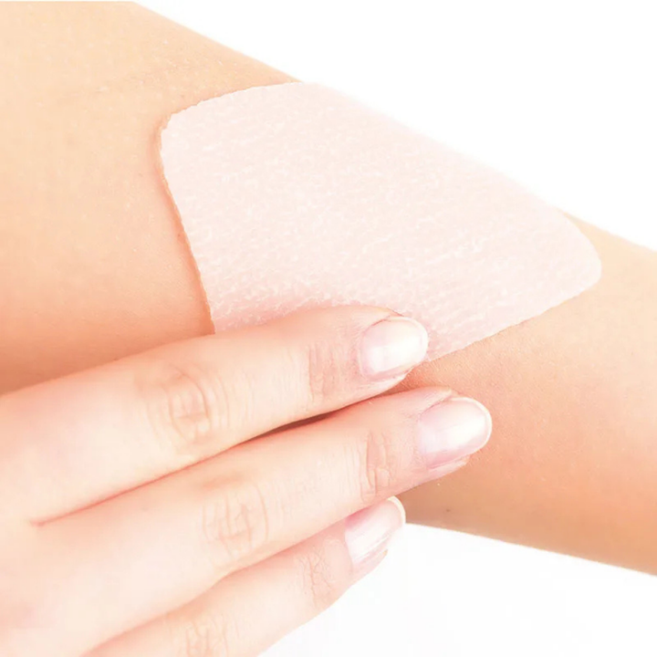 Silicone sheets in pale pink, flexible medical-grade material, shown being applied to skin for scar care