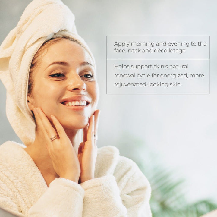 Young woman with towel turban and white robe gently touching her glowing skin, demonstrating Skinbetter Science Alto Defense skincare routine