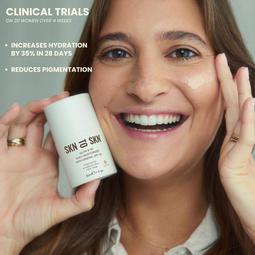 Skn to Skn Glow & Go daily moisturiser in a white bottle with a light tint, shown beside a smiling woman